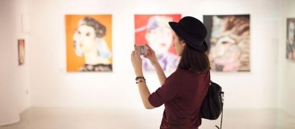 girl visiting museum and taking pictures of art